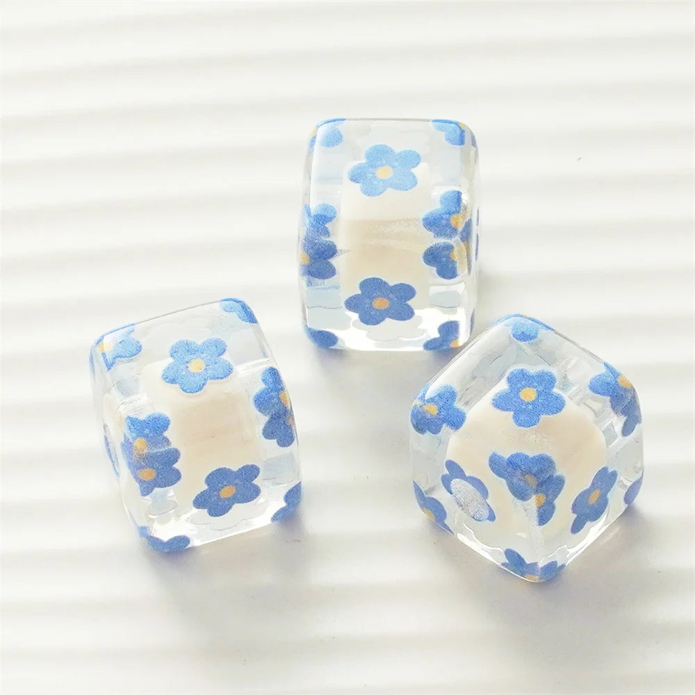 Three clear resin square beads with blue floral patterns for DIY jewelry making