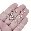 A hand holds various acrylic star and heart spacer beads for jewelry making in gold and silver tones.