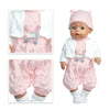 A baby doll wearing a pink outfit set with a cat print shirt and a matching hat.