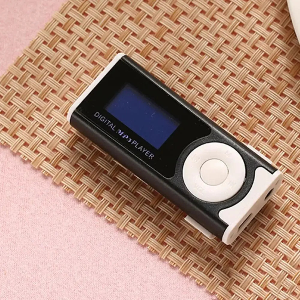Ein schwarzer digitaler MP3-Player mit weißer Taste liegt auf einer geflochtenen Strohmatte.