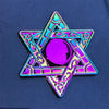 A purple and iridescent metal fidget spinner shaped like a five-pointed star with intricate patterns.