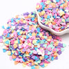A pile of colorful polymer clay sprinkles in various shades of pink, purple, and yellow hearts.