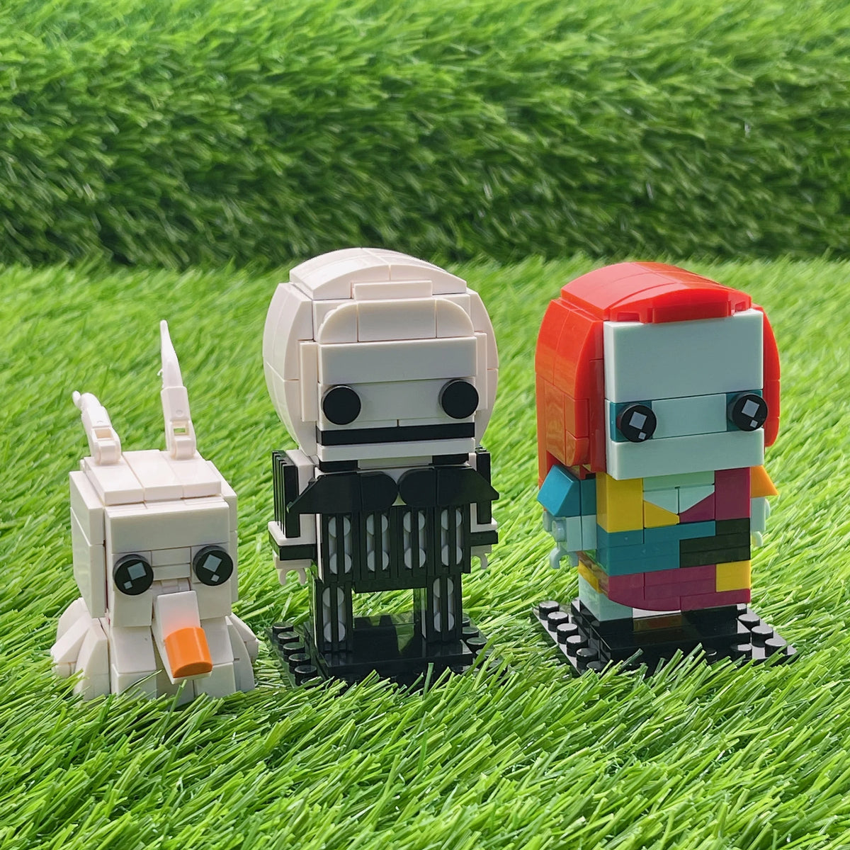 A set of three LEGO minifigures representing characters from The Nightmare Before Christmas standing on green grass.