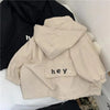 A beige kids hooded letter print zip-up jacket laid on a white surface.