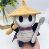 A soft plush doll resembling a character with a tan hat and purple accents is held in a hand.