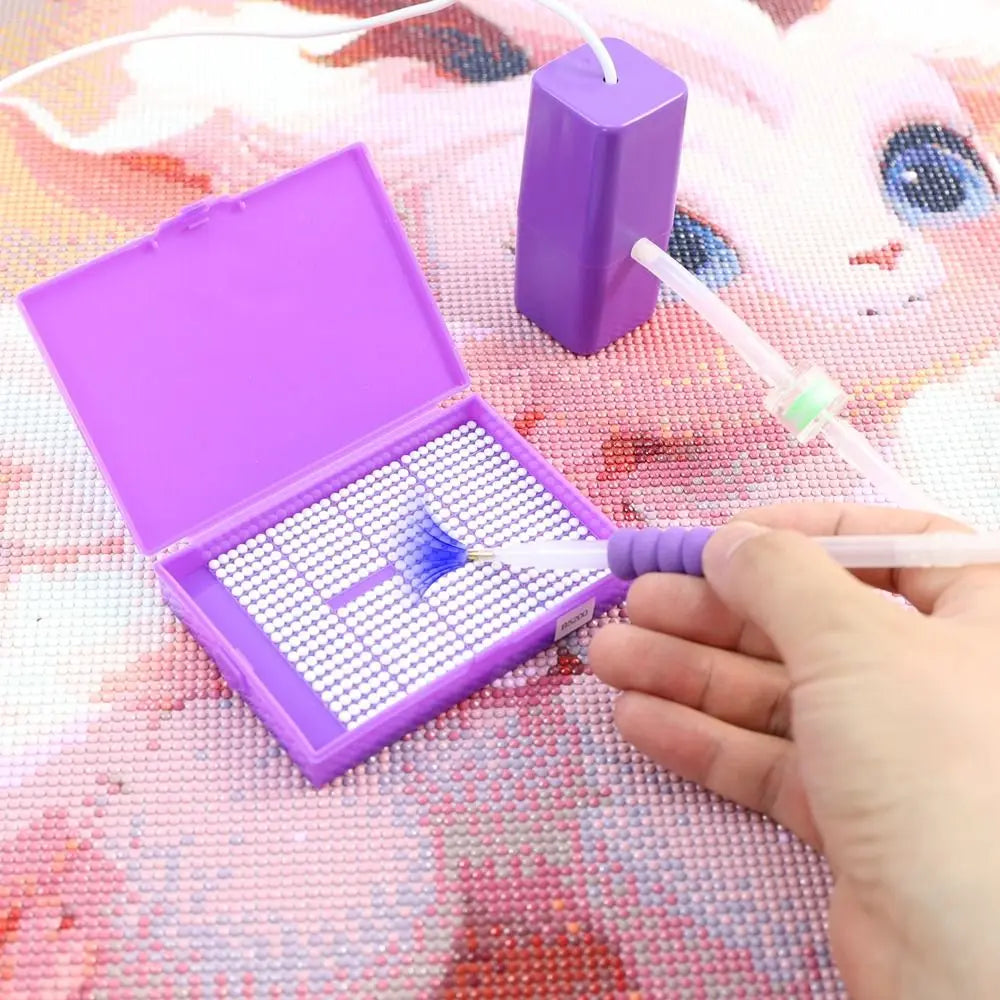 A hand is using a white pen to apply glitter onto a purple diamond painting canvas inside an open purple box.