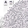 A close-up view of white acrylic alphabet and number beads scattered on a white background.