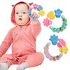 A baby is holding a silicone teether ring with various colored silicone shapes.
