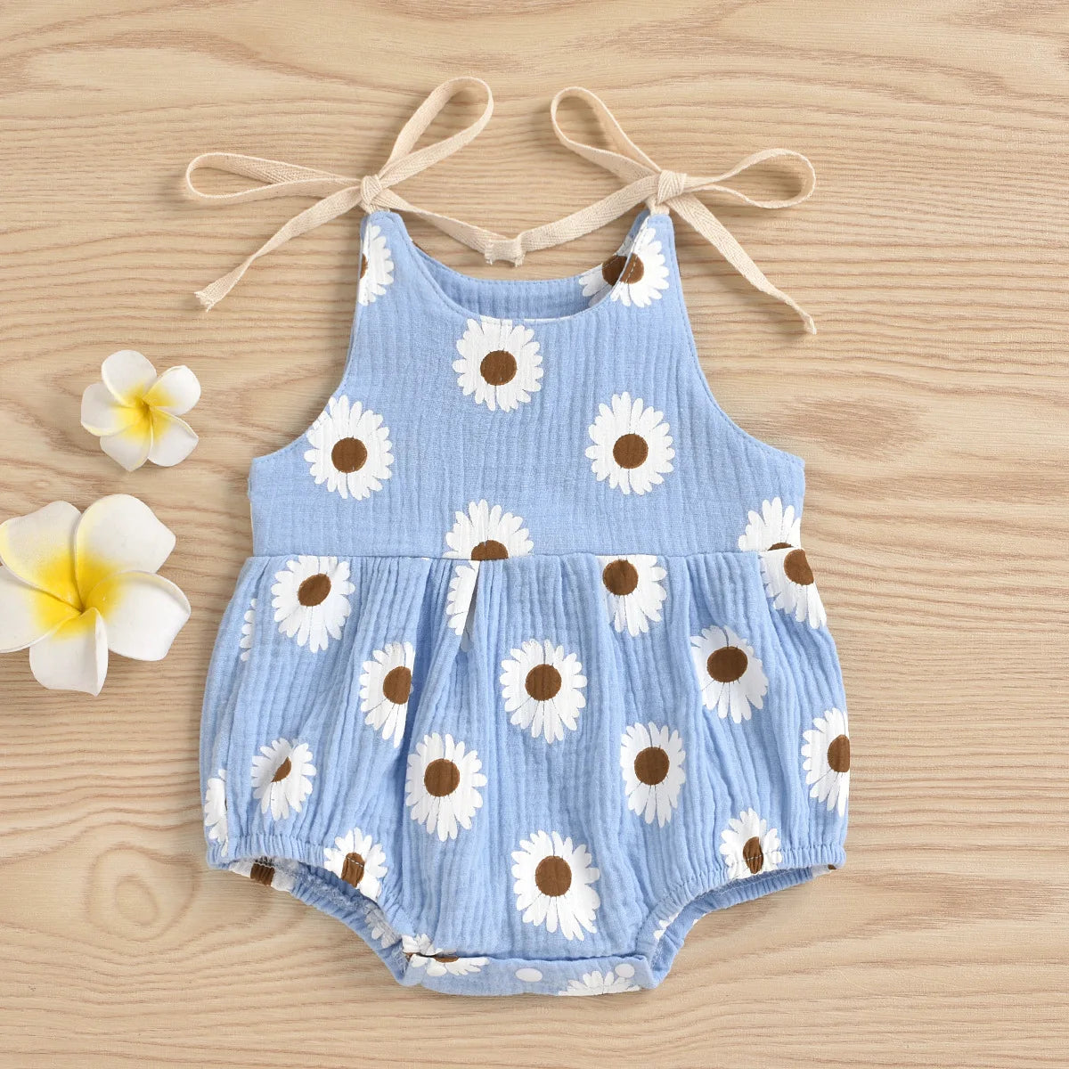 Light blue cotton romper for a baby girl with a white daisy floral print and adjustable ties