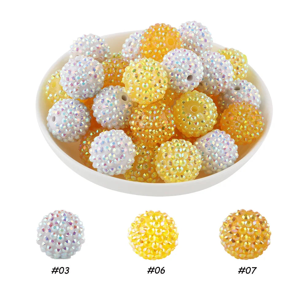 A bowl filled with various colors of rhinestone resin bayberry beads for jewelry making, including shades of white, yellow, a