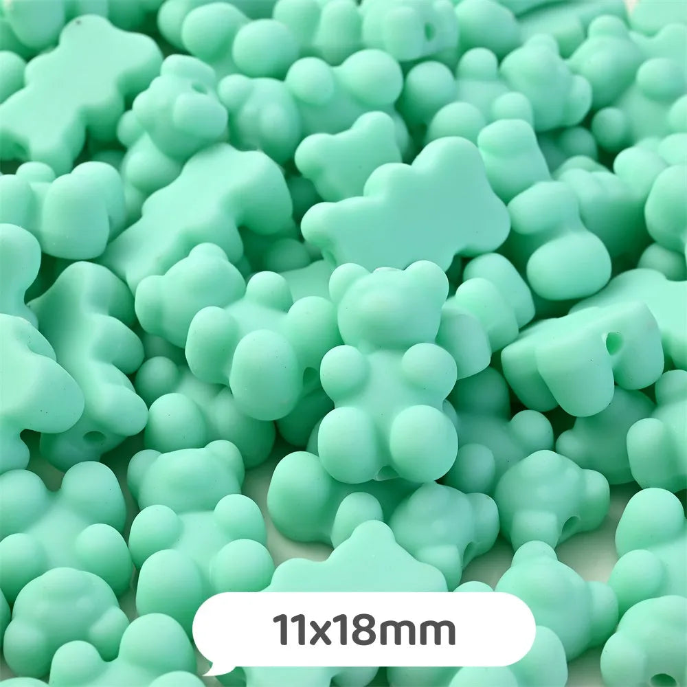 A pile of pastel green bear-shaped acrylic craft beads with a shimmer finish