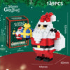 A white and red Santa figure built from micro building blocks, standing next to a green Christmas wreath.