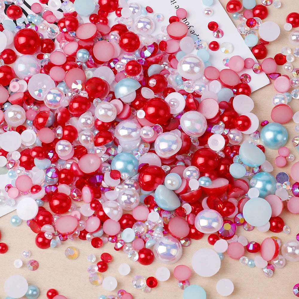 A colorful mix of red, pink, and blue resin rhinestones and pearls with an AB finish scattered on a light wooden surface.