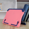 A pink adjustable portable book stand with blue accents resting on a wooden surface next to a blue binder.