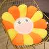 A large sunflower plush cushion with orange and yellow petals is displayed in a gold wire basket.