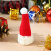 A red and white knitted Christmas hat displayed among festive gold and red holiday decorations.