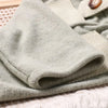 A light sage green knit romper and newsboy cap set for a newborn boy photography outfit.
