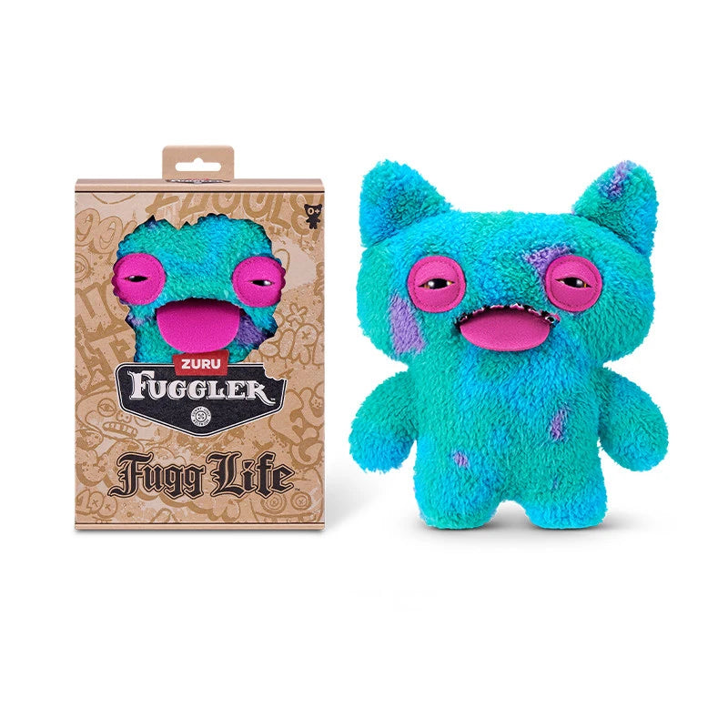 A bright blue Fuggler plush toy monster with large pink eyes and a purple version in its packaging.
