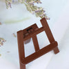 A small, dark brown wooden artist easel for a dollhouse, positioned next to dried lavender.