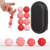 A hand holds a string of pink and red magnetic sensory fidget balls next to a black zippered pouch and several loose balls.