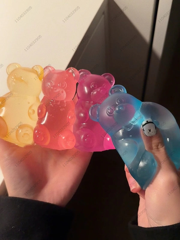 Une main tient plusieurs jouets anti-stress en gélatine de forme de oursons colorés dans différentes nuances de jaune, rose e