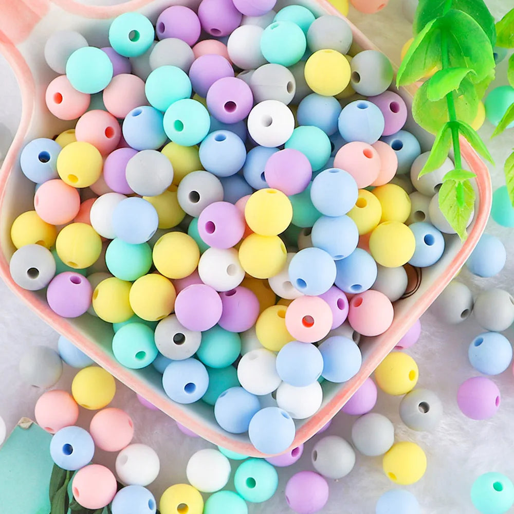 A close-up of 50 assorted silicone beads in various pastel colors like pink, blue, yellow, and purple.