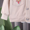 A light pink corduroy jacket with a decorative patch is shown on a hanger.
