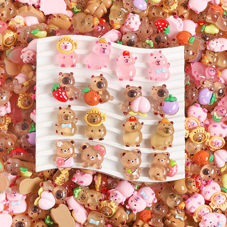 A close-up of numerous small resin figurines shaped like capybaras and other cute animals in various colors scattered on a su