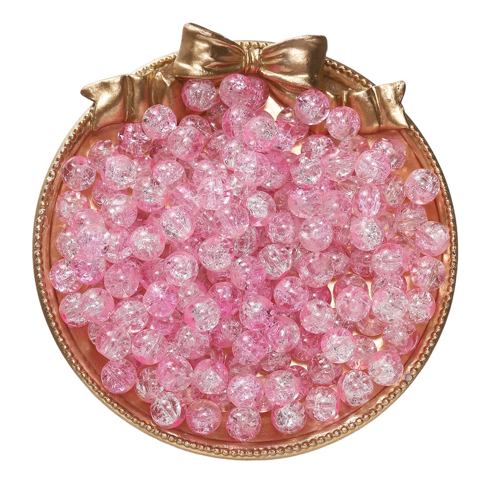 A circular display of pink glass crackle beads arranged in a mound, tied with a gold bow.