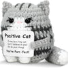A gray and white crocheted cat plush toy with a positive message tag that reads You're Purr-fect