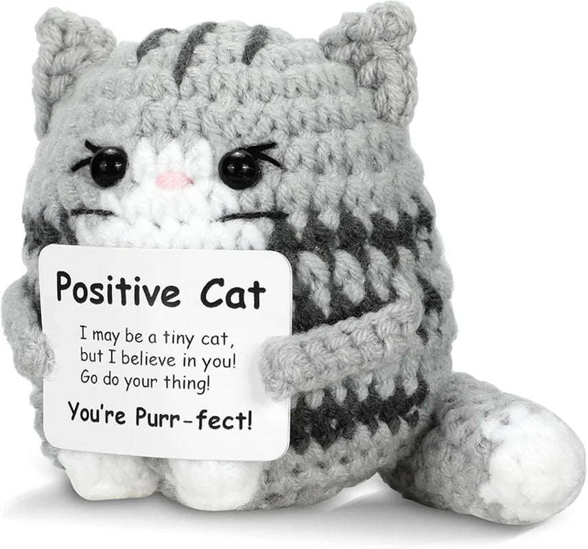A gray and white crocheted cat plush toy with a positive message tag that reads You're Purr-fect