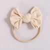 A beige knitted fabric bow headband with a soft elastic band.