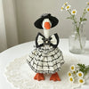 A handcrafted mini goose statue dressed in a black and white plaid outfit with a bow and floral accessories.