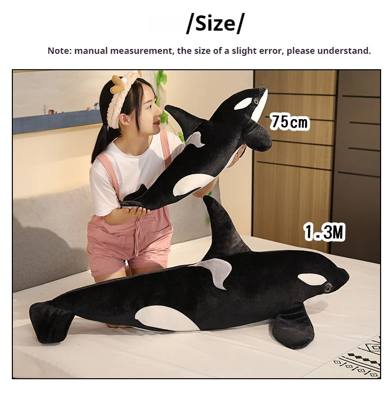 A black and white lifelike orca whale plush toy is displayed next to a person for scale, with dimensions of 75cm and 1.3m.