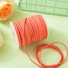 A roll of orange velvet faux suede braided ribbon for crafting and gift wrapping is shown on a light green surface.