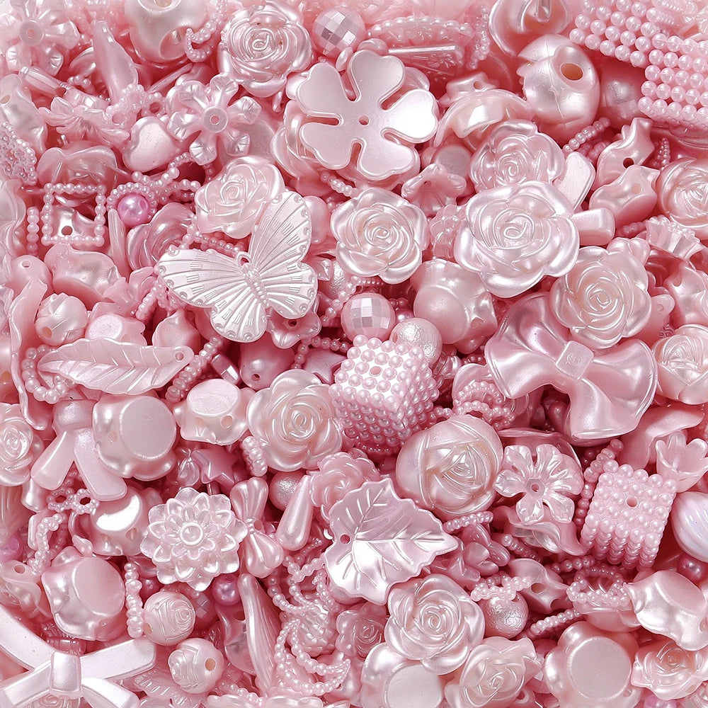 Close-up of pink and iridescent acrylic beads, including butterfly and rose shapes, for DIY jewelry making.