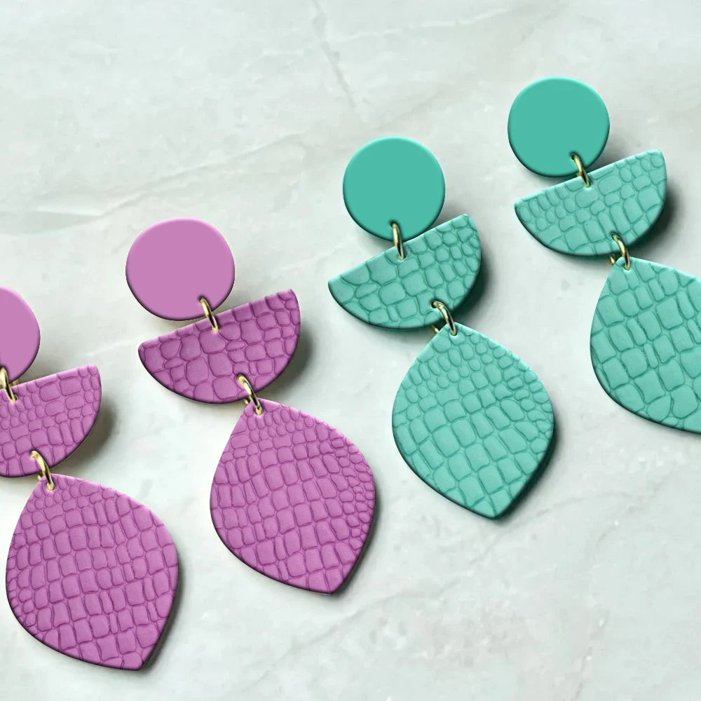 A set of floral and leaf clay texture rollers in pink and teal colors for making handmade jewelry.