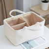Un sac organisateur moelleux de couleur crème avec un couvercle est montré sur une surface blanche à côté d'un magazine.