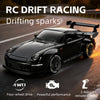 Black RC drift racing car driving on a road with sparks, featuring four-wheel drive and remote control.