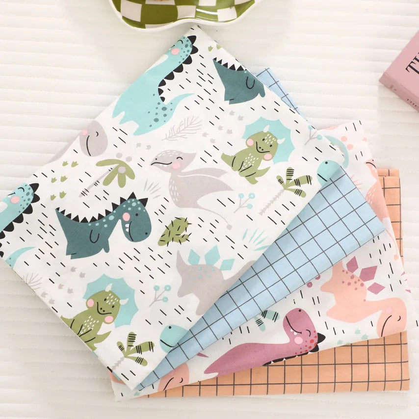 A stack of fabric featuring a dinosaur grid print in various colors like teal, green, and pink.