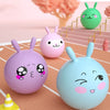 A collection of pink and blue inflatable hopper balls shaped like rabbits are displayed on a wooden surface.