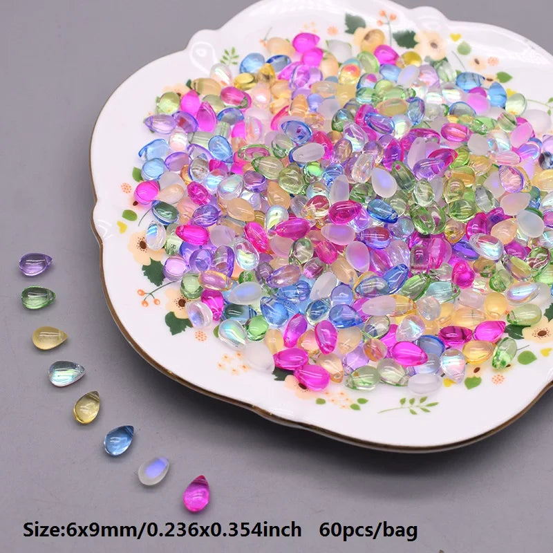 A plate filled with colorful water drop Czech glass beads for jewelry making, displayed alongside loose beads.