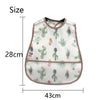 A white baby bib with a green cactus pattern and a brown trim.