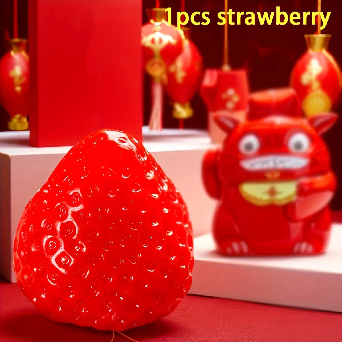 A bright red strawberry squishy fidget toy is shown in a close-up against a red background.