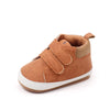 A pair of brown soft PU leather baby first walker shoes with a white anti-slip sole.