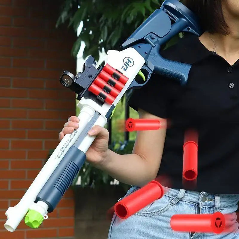 A hand holds a blue soft bullet shotgun toy with red shells, demonstrating the shell ejecting action.