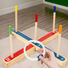 A hand is holding a white ring on a wooden ring toss game with colored wooden pegs and numbers.