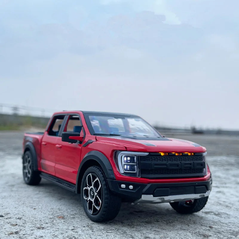 A red 1:20 scale Ford Raptor F150 diecast model truck parked on a gray, open surface.