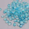 A pile of small, translucent blue glass beads resembling tulip flowers.