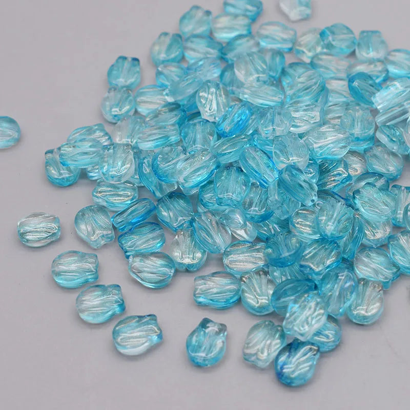 A pile of small, translucent blue glass beads resembling tulip flowers.